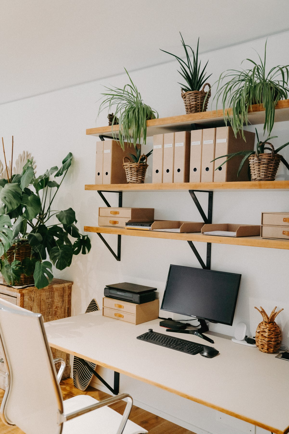 Homeoffice mit Regalwand, Schreibtisch, Stuhl umgeben von Pflanzen
